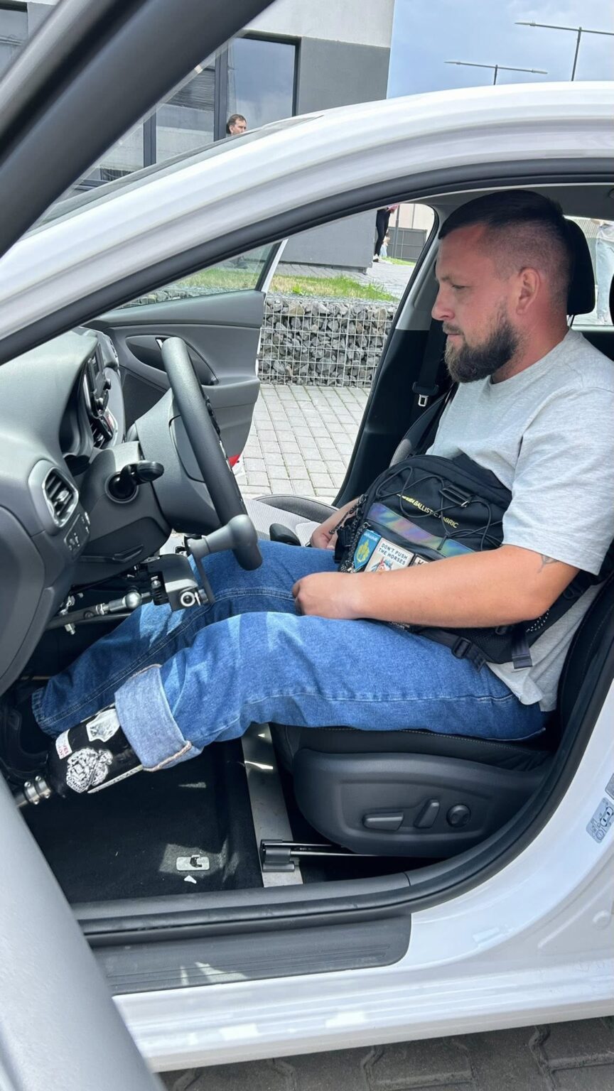 Чоловік сидить в автомобілі з протезом ноги.