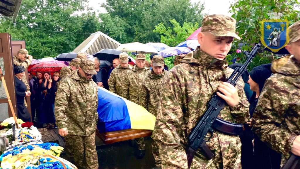 Похорон військових у дощову погоду з прапорами.