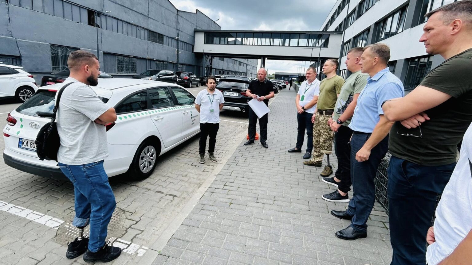Люди збираються навколо білого автомобіля на вулиці.