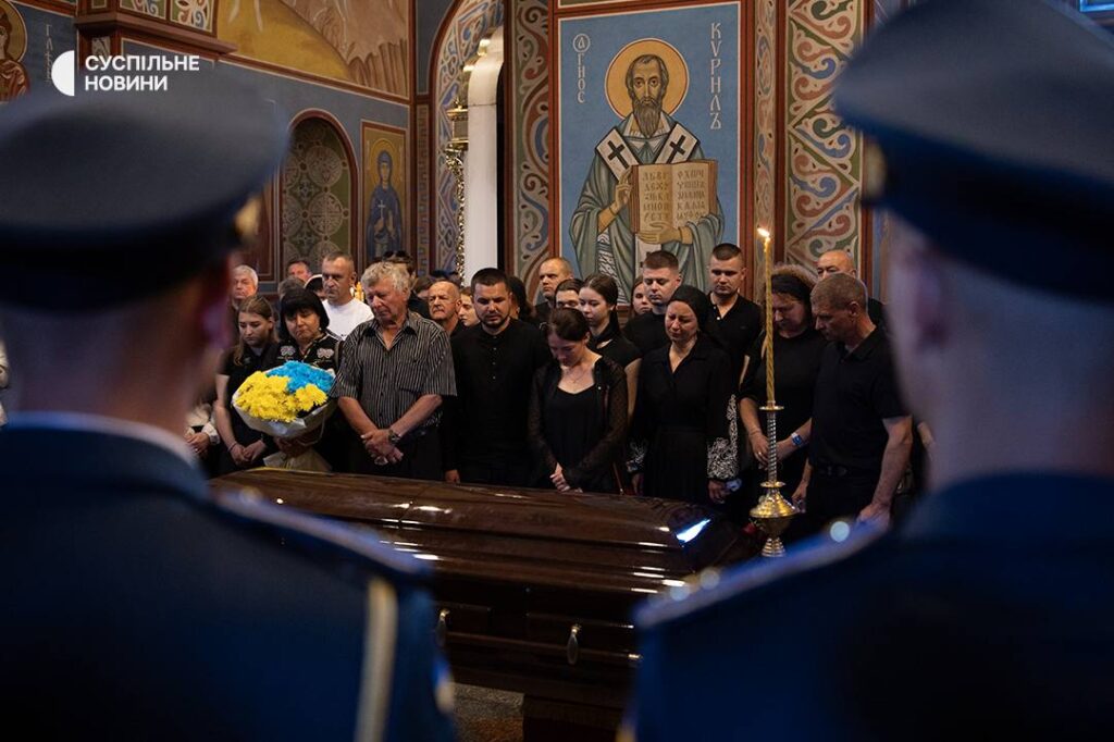 Люди на похороні в церкві з труною.