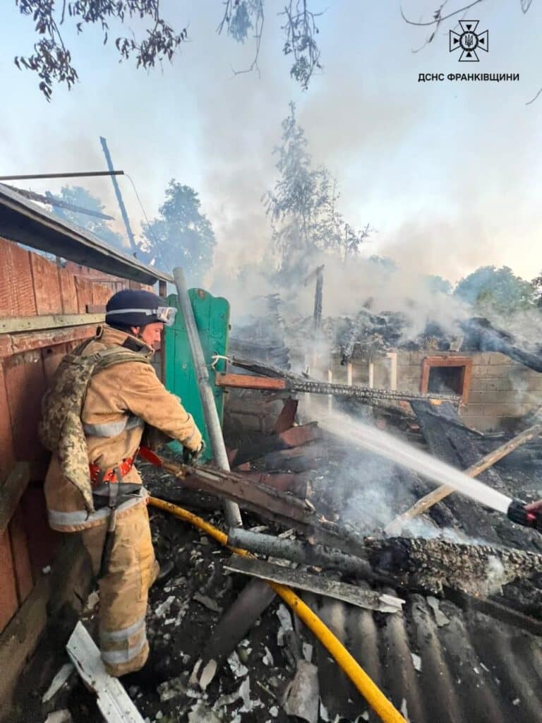 Пожежник гасить вогонь у будівлі, сильний дим.