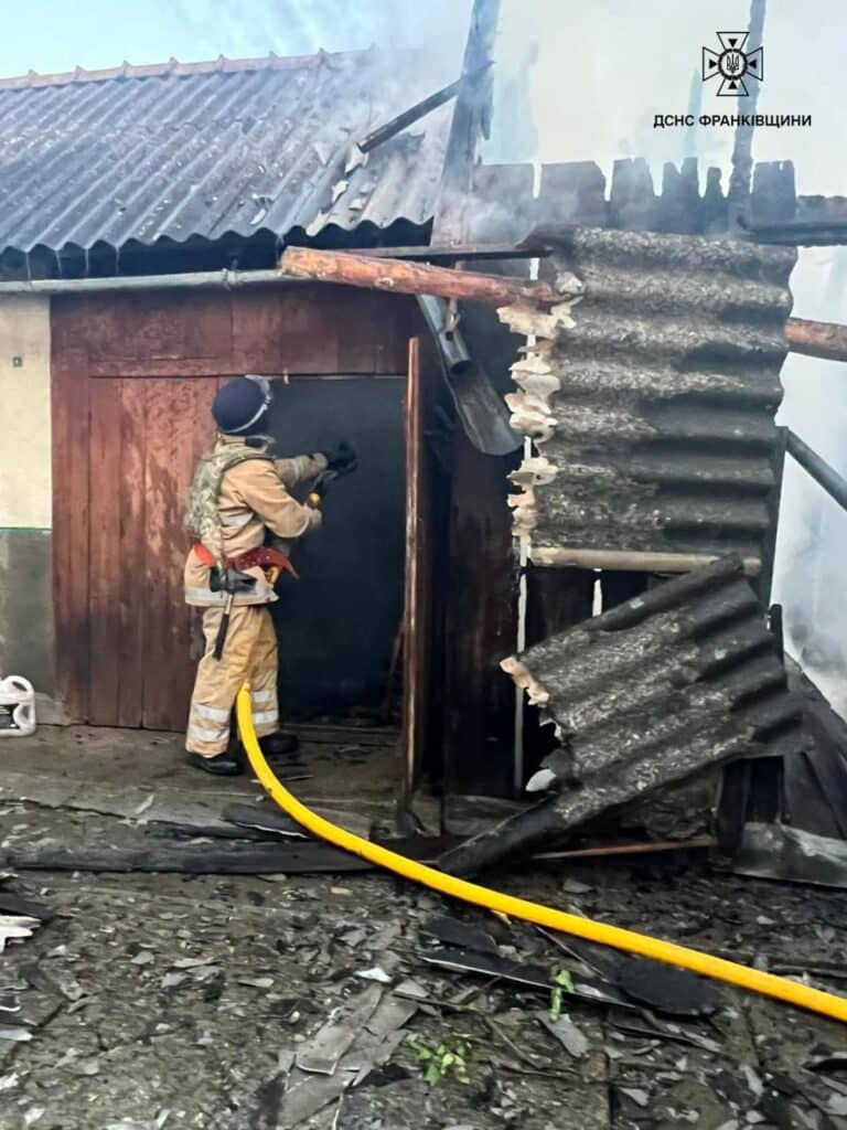 Пожежник гасить вогонь у дерев'яній будівлі