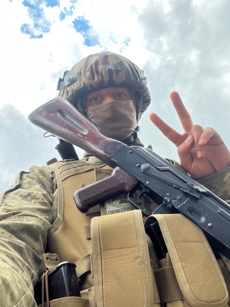 Український солдат з автоматом, робить знак миру.