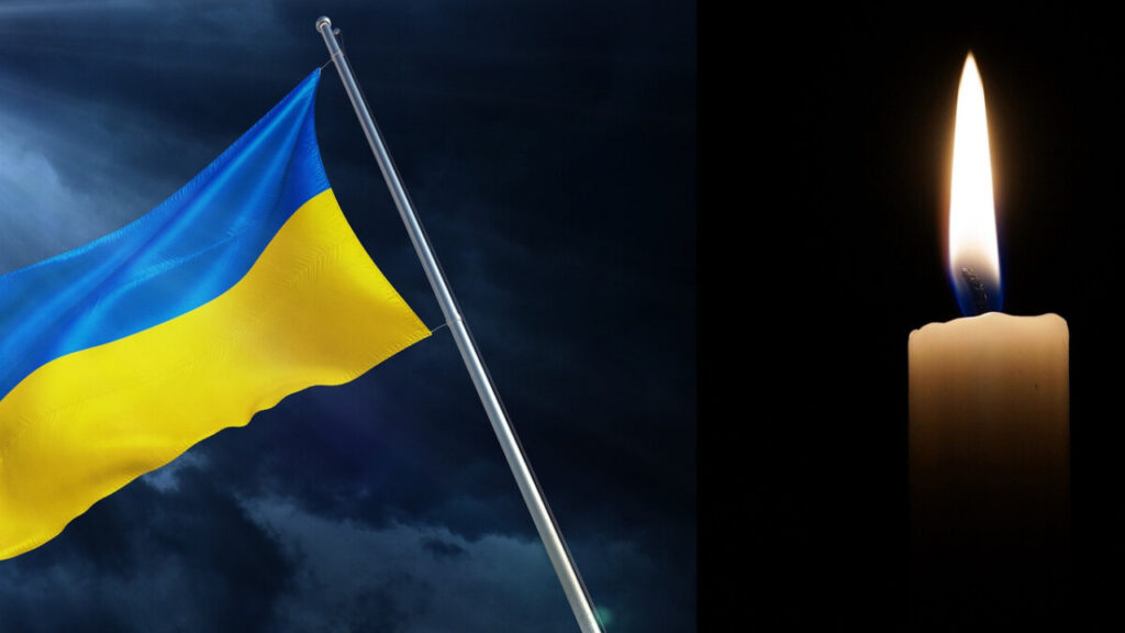 Український прапор і свічка на темному фоні.