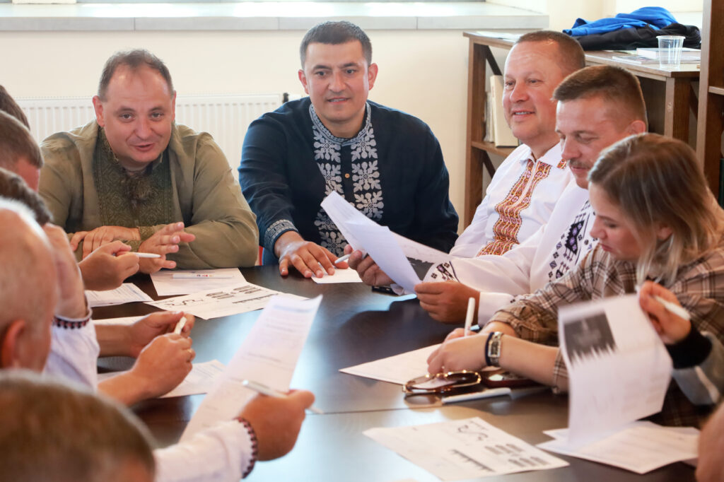 Люди у вишиванках обговорюють документи на нараді.