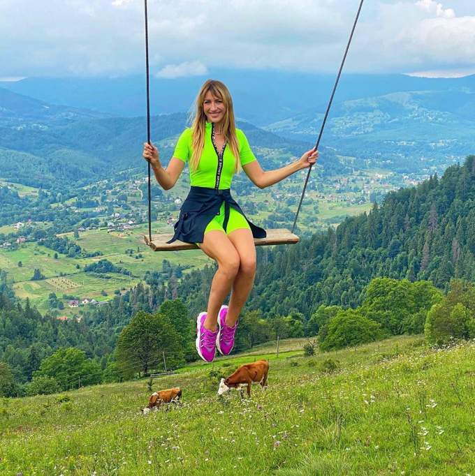 Дівчина на гойдалці в горах, корови пасуться.