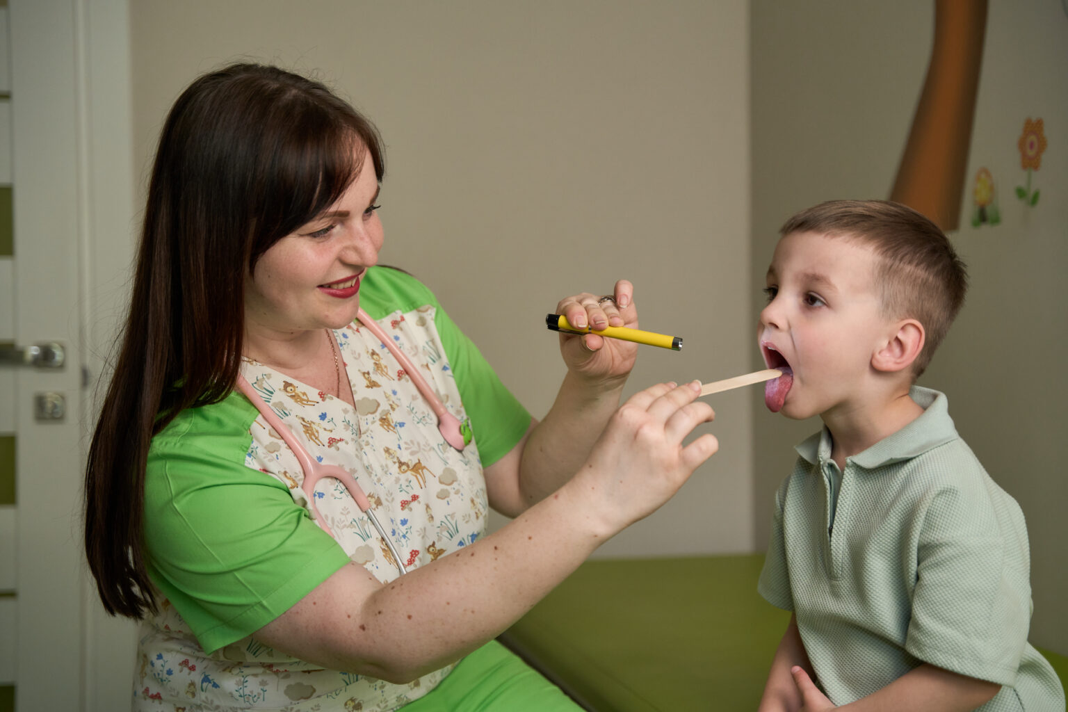 Дитячий лікар досліджує горло хлопчика