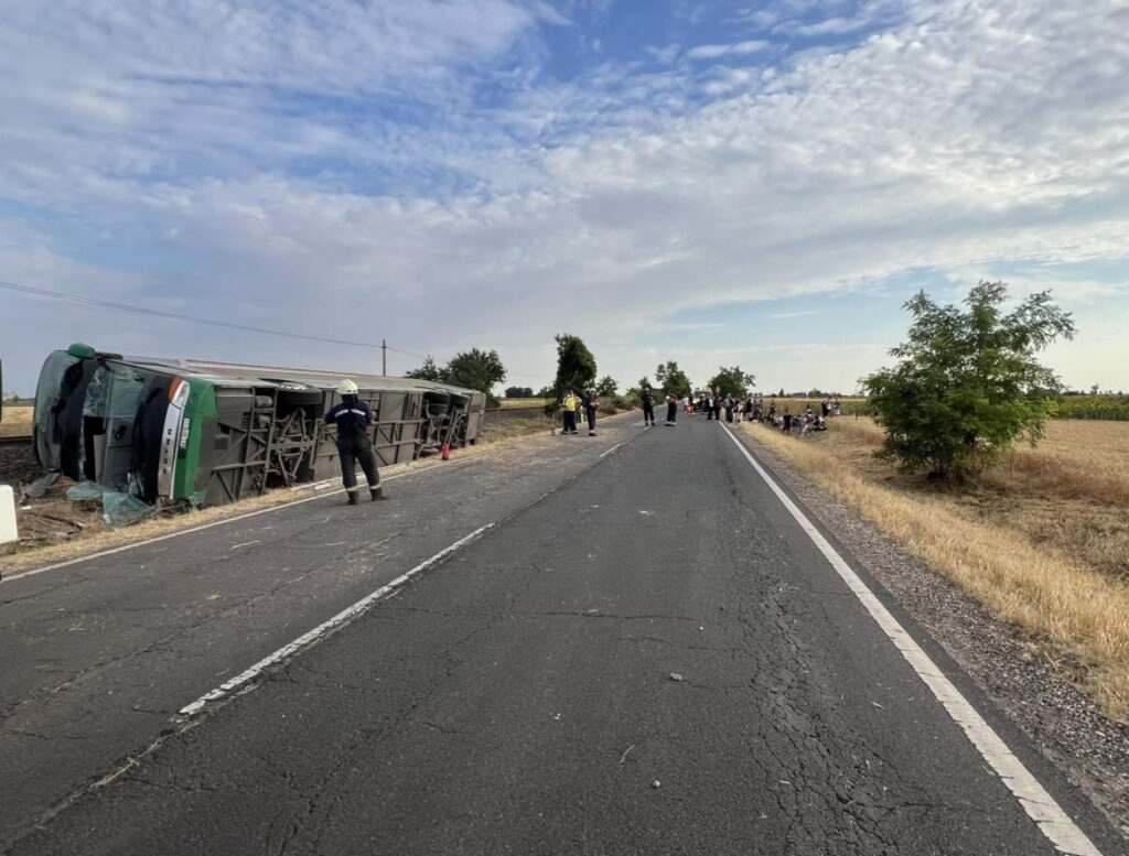 Перекинутий автобус на дорозі, люди навколо