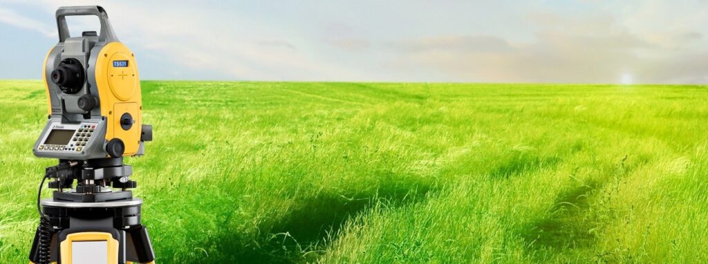 Теодоліт на зеленому полі під небом