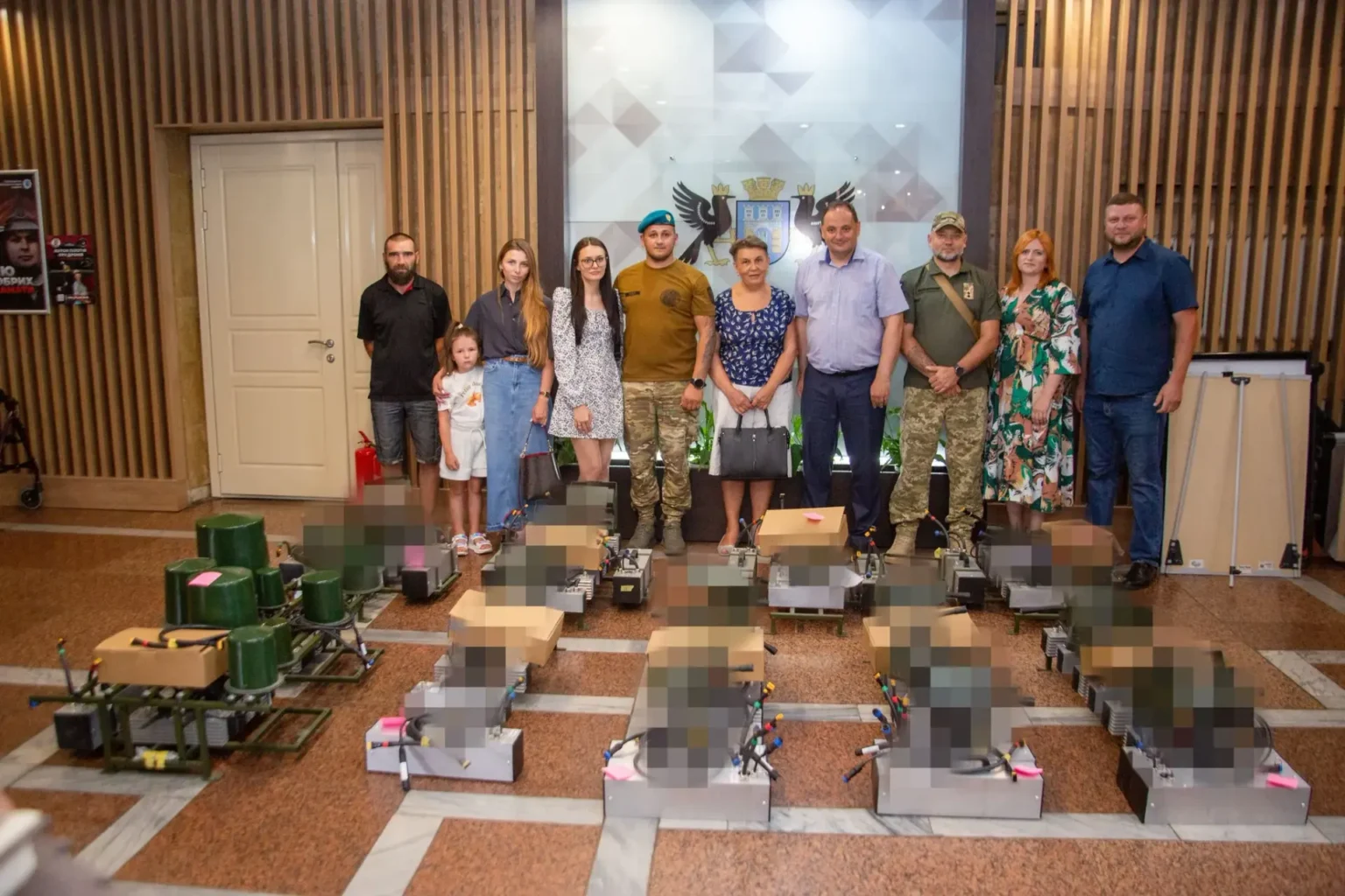 Групове фото людей із військовою технікою в приміщенні.