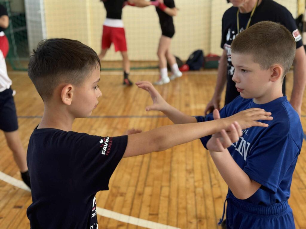 Діти тренуються в спортзалі на дерев'яній підлозі.