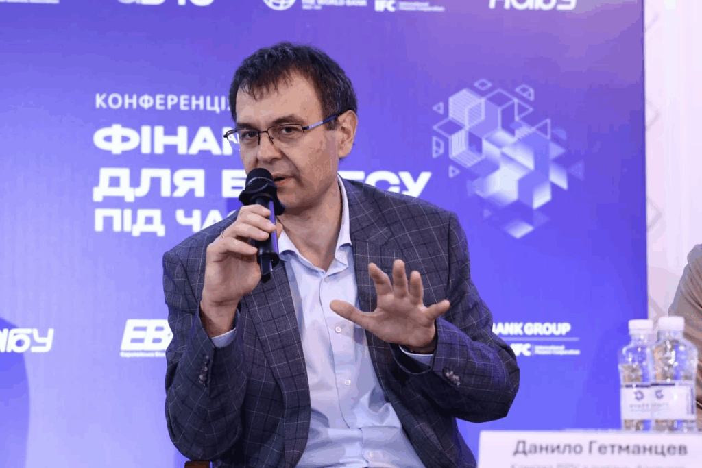 Чоловік на конференції, говорить у мікрофон.