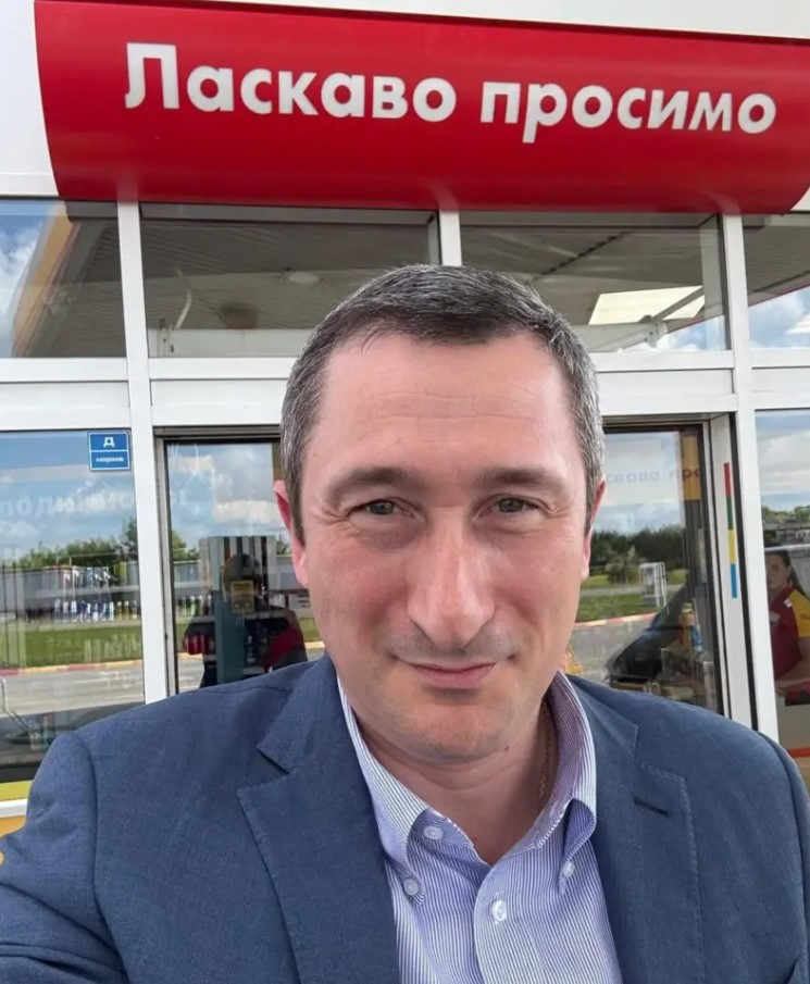Чоловік на фоні вивіски 'Ласкаво просимо'