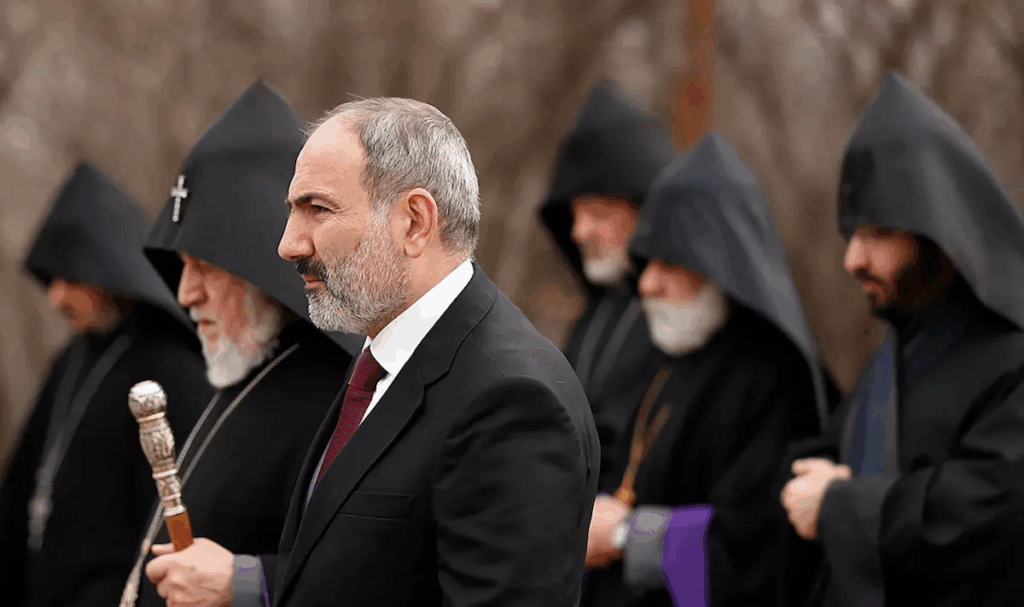 Чоловік у костюмі серед людей у чорних вбраннях.