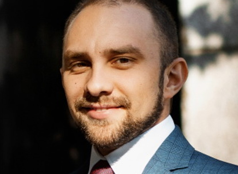 Чоловік у синьому піджаку, усміхається