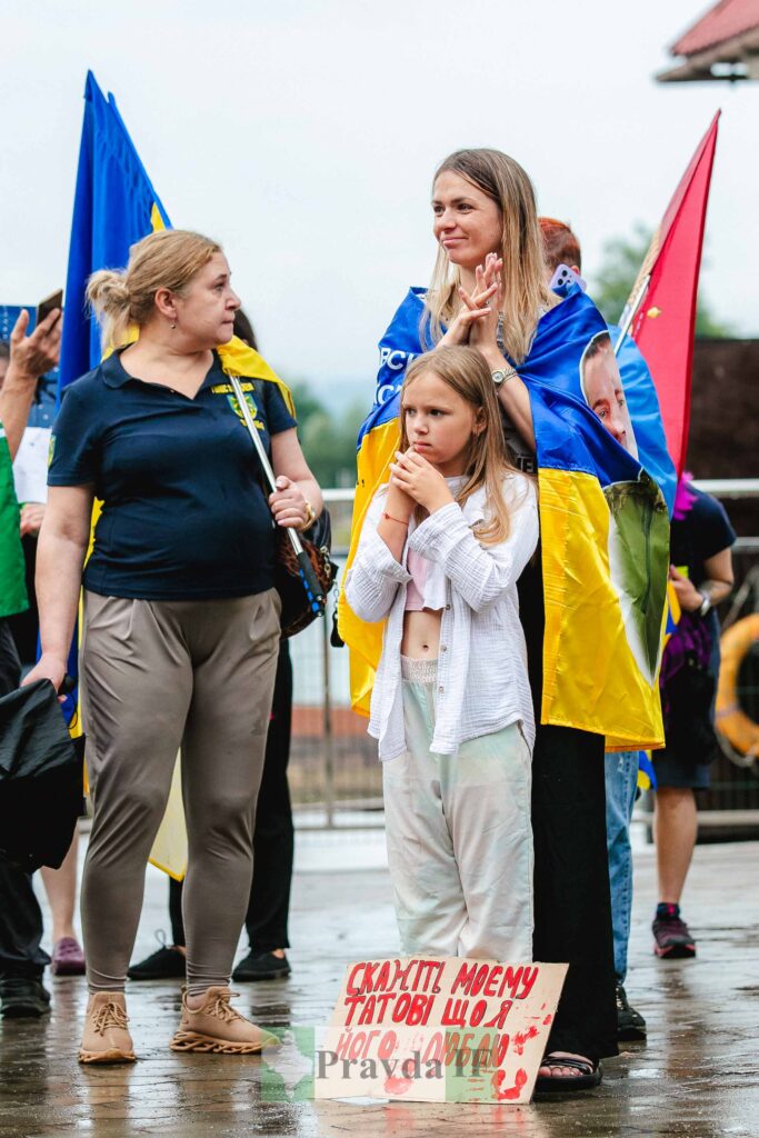 Люди на протесті з українськими прапорами.