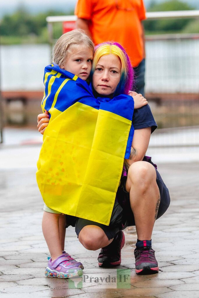 Жінка і дитина з українським прапором на вулиці.