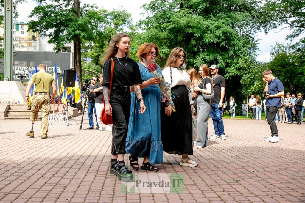 Церемонія вшанування героя з квітами та прапорами.
