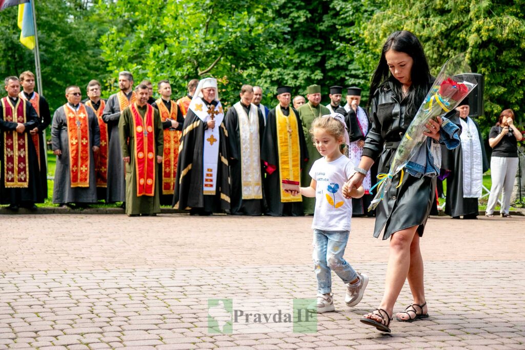 Жінка з дитиною та квітами, і священнослужителі