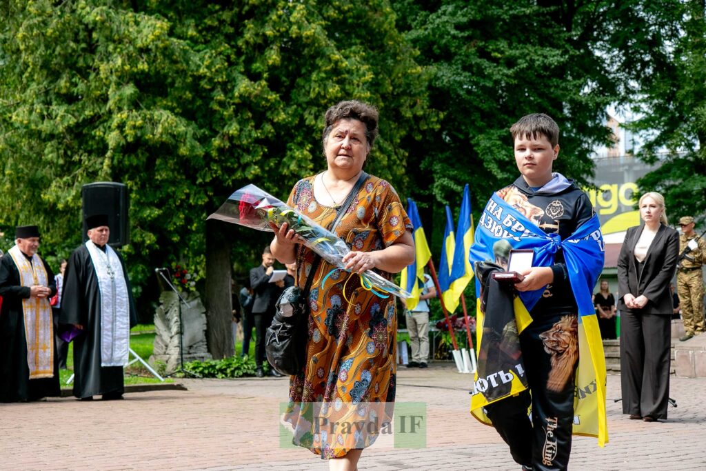 Жінка з квітами на пам'ятній церемонії в Україні.