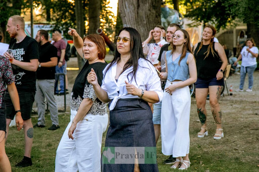 Люди танцюють на відкритому повітрі, весела атмосфера.