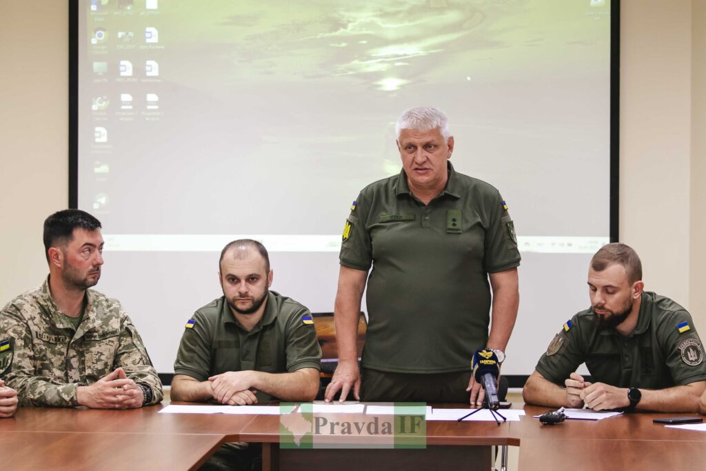 Військові на пресконференції з мікрофоном на столі.