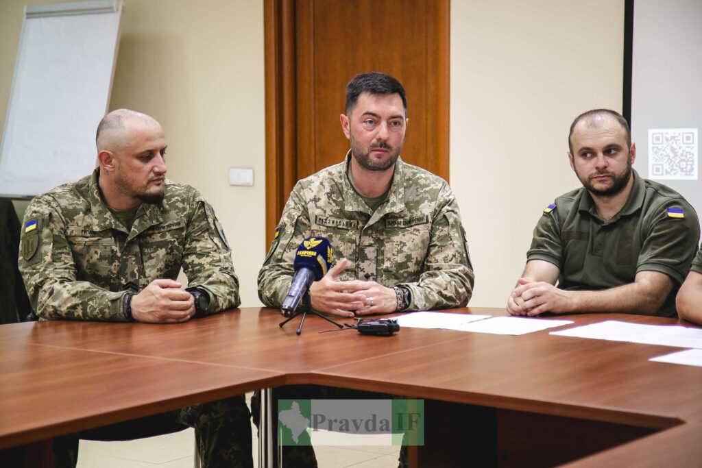 Військові обговорюють нараду за столом з мікрофоном.