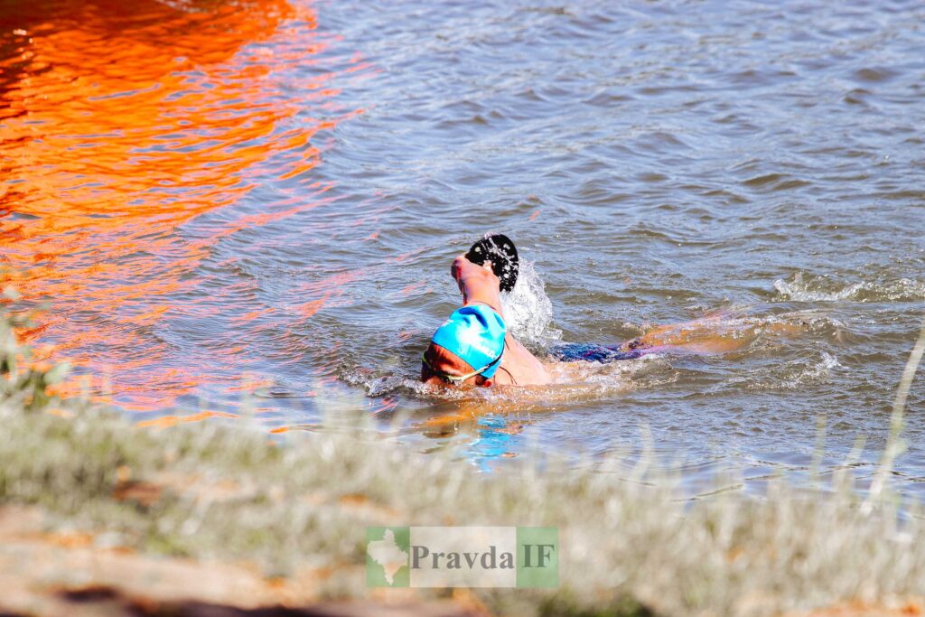 Плавець у блакитній шапочці пливе в річці