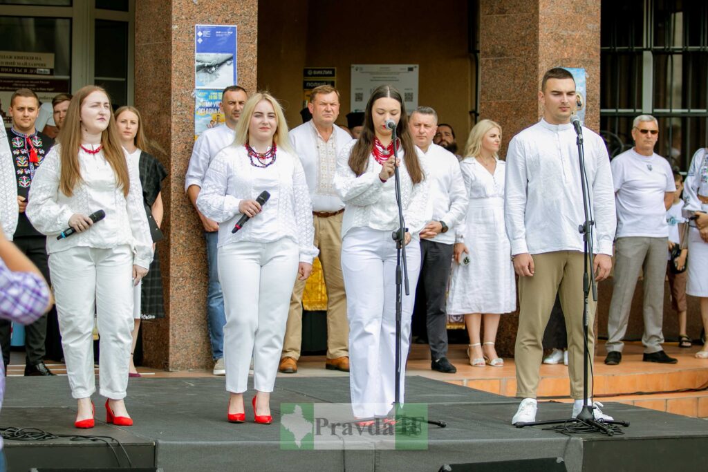Люди у вишиванках співають біля мікрофонів.