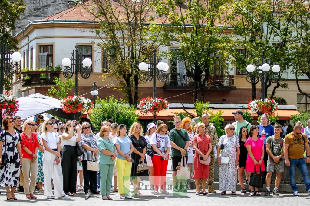 Люди на вулиці біля старої будівлі, сонячний день.