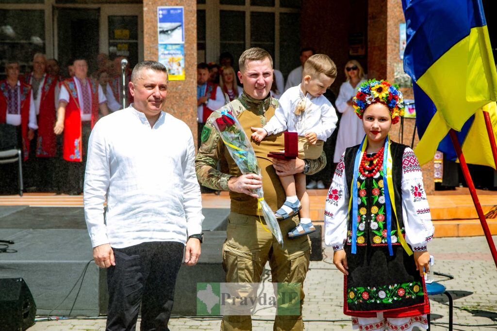 Урочиста подія з людьми у вишиванках та прапором.