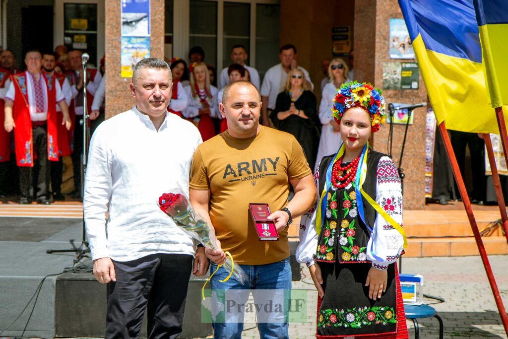 Троє українців на церемонії нагородження, прапори України.