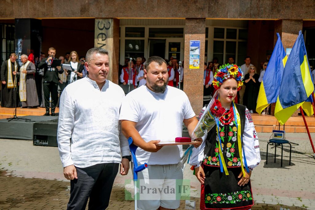 Церемонія вручення нагород біля будівлі, українські прапори.