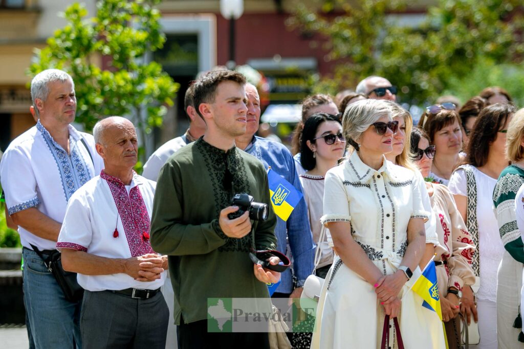 Люди у вишиванках з українськими прапорами на вулиці.