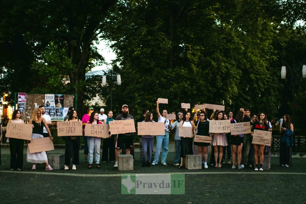 Люди з плакатами на вуличному протесті, вечір.