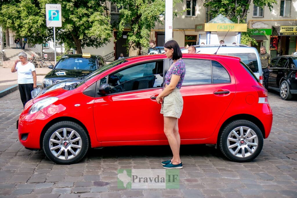 Жінка поруч з червоним автомобілем на вулиці