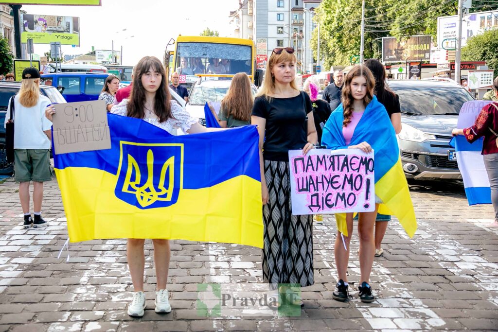 Люди на демонстрації з прапором України та плакатами.
