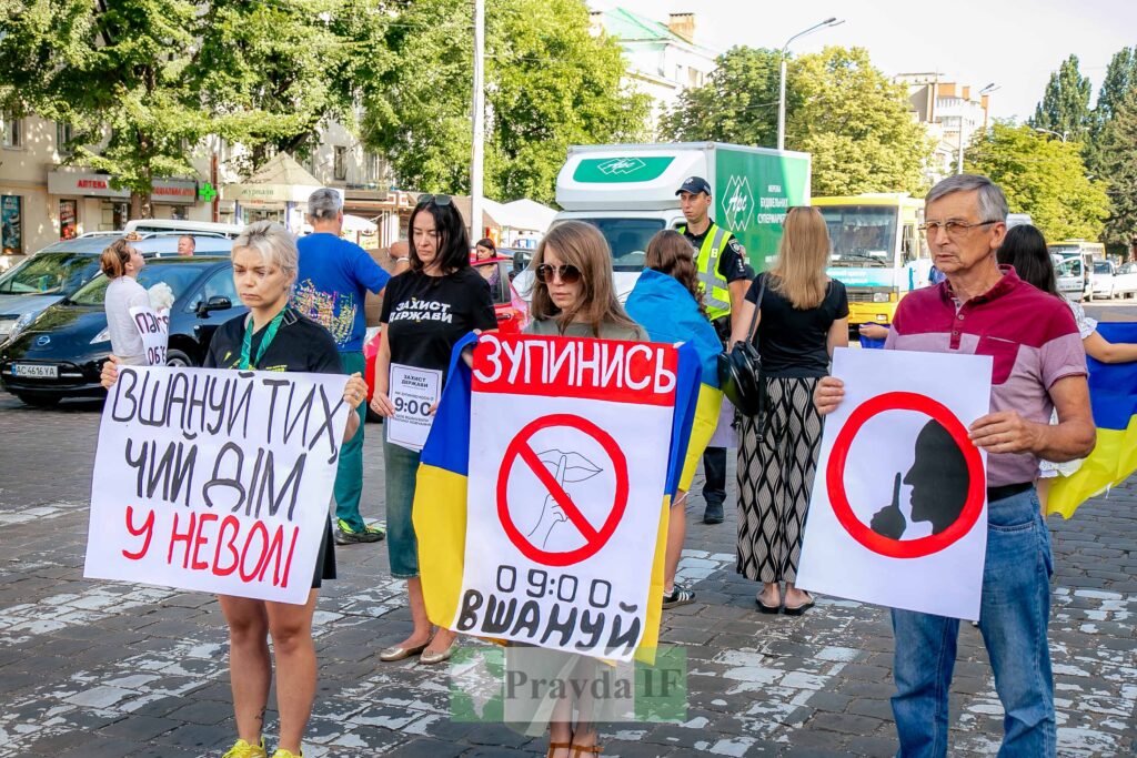Люди на протесті з плакатами і прапором
