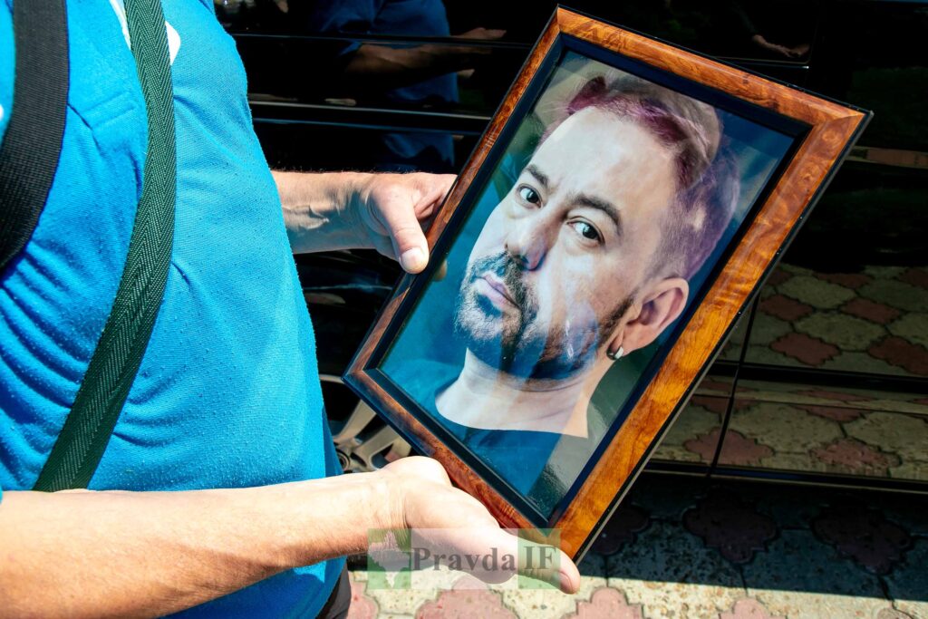 Чоловік тримає портрет у рамці.
