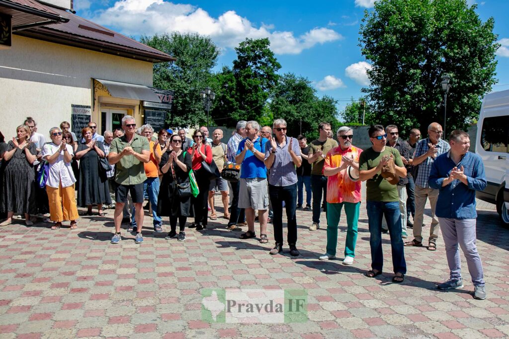 Група людей аплодує на вулиці під сонцем.