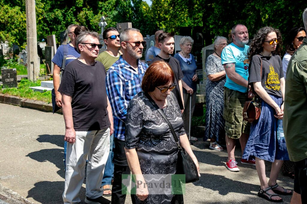 Люди стоять на кладовищі під час похорону
