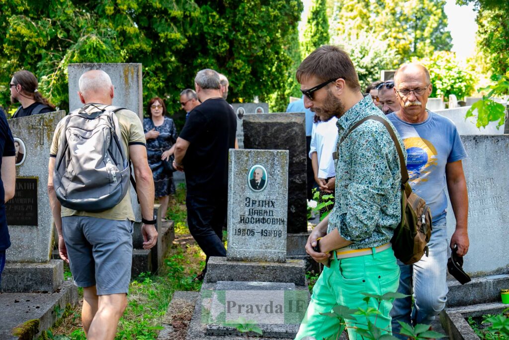Люди на кладовищі біля надгробків влітку.