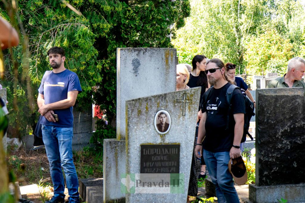 Люди біля могил на цвинтарі влітку.