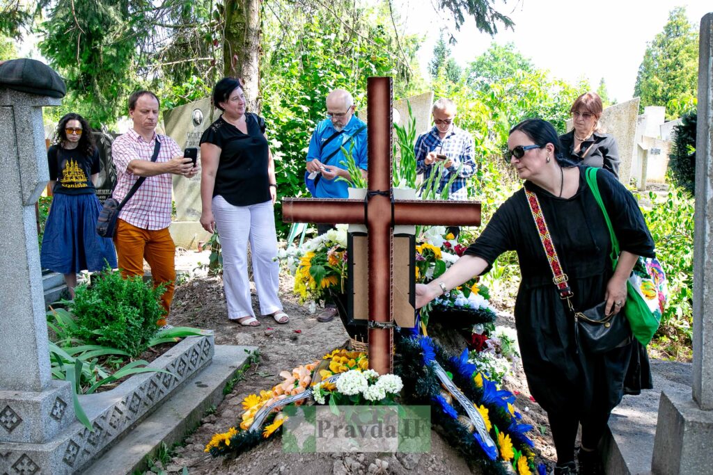Люди вшановують пам'ять на могилі з квітами.
