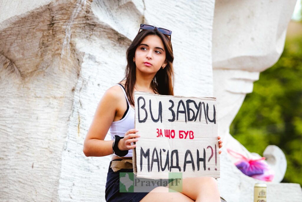 Молода жінка з плакатом на майдані.