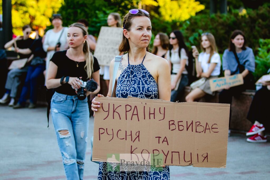 Жінка тримає плакат на мітингу.
