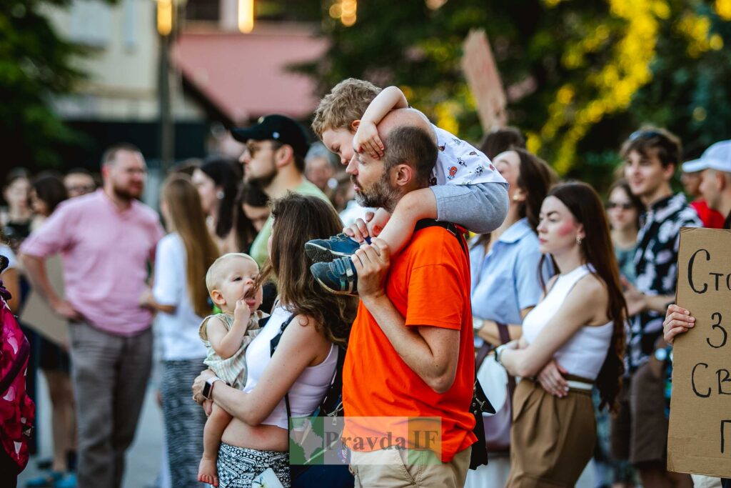 Люди на мітингу, дитина на плечах чоловіка.