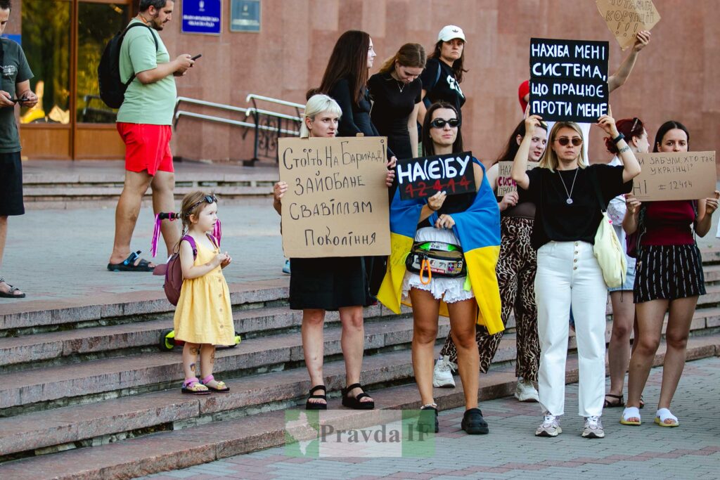Протест на вулиці; люди тримають плакати.