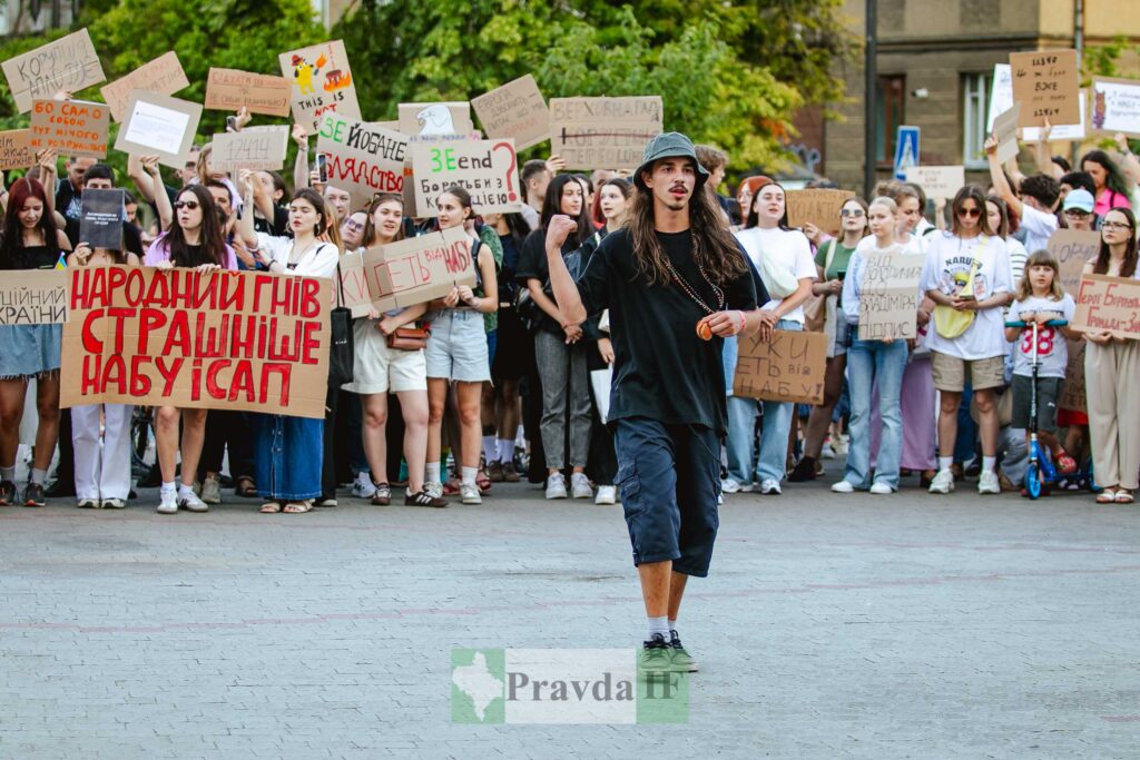 Протест на вулиці з плакатами та людьми.
