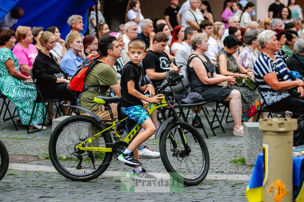 Хлопчик сидить на велосипеді серед людей на заході.